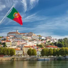 Wspaniała portugalia pogoda roczna, z flagą Portugalii powiewającą nad malowniczym miastem na wzgórzu, nad rzeką.