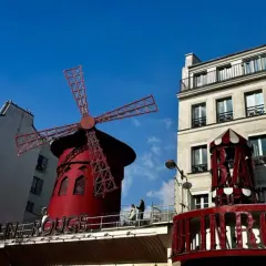 Słynny czerwony wiatrak Moulin Rouge na tle błękitnego nieba.