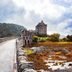 Kamienny most prowadzi do zamku Eilean Donan. Mglisty, jesienny klimat Szkocji podkreśla surowe piękno krajobrazu.