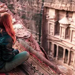 Niesamowita petra jordania wycieczka. Kobieta siedzi na dywanie, podziwiając Skarbiec wykuty w skale.