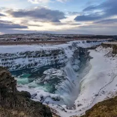 Potężny wodospad Gullfoss, część Złotego Kręgu Islandii, w zimowej scenerii. Woda spływa kaskadami do kanionu, otoczonego śniegiem i lodem.