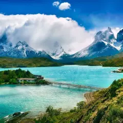 Malownicze jezioro w Patagonii, Chile. W oddali ośnieżone szczyty górskie, a na brzegu domki z pomostem. Idealne miejsce na podróż, marzenie o wizie do Chile.