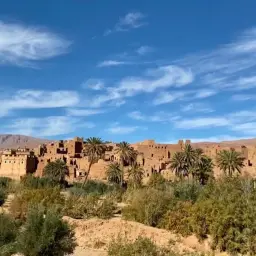 Krajobraz z glinianymi domami i palmami pod błękitnym niebem. Czy to właśnie tam, gdzie jest Marrakesz?