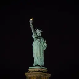 Statua Wolności nocą, z płonącą pochodnią. Marzysz o zobaczeniu jej na żywo? Sprawdź bilety!