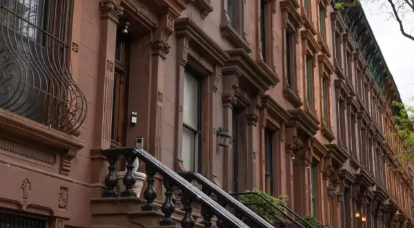 Brązowe kamienice w stylu brownstone, typowe dla Harlem, Nowy Jork, z ozdobnymi detalami i schodami.
