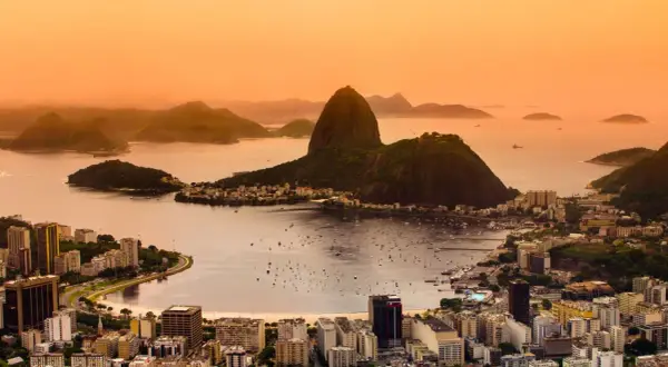 Widok na Rio de Janeiro o zachodzie słońca. W tle góry i zatoka z łodziami. Marzenie o podróży do Brazylii i szczepienia na wyjazd.