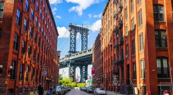 Ulica w dzielnicy DUMBO, Queens, Nowy Jork, z widokiem na most Manhattan Bridge między ceglanymi budynkami.