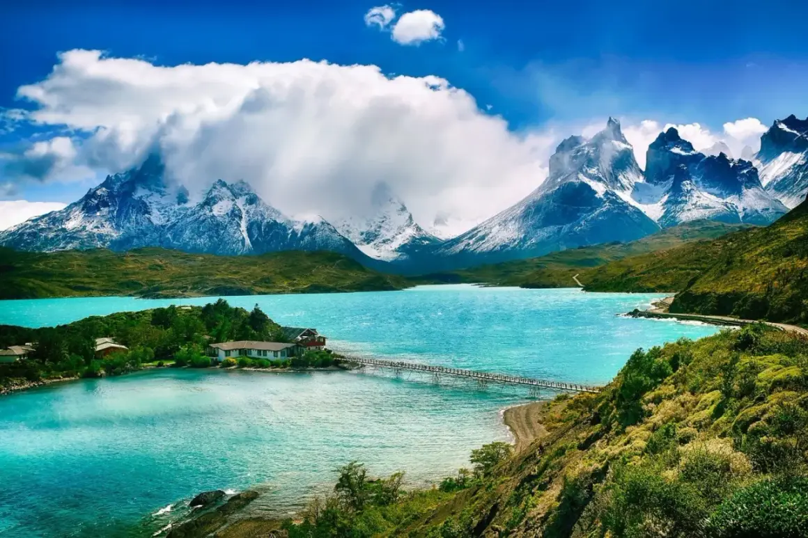Malownicze jezioro w Patagonii, Chile. W oddali ośnieżone szczyty górskie, a na brzegu domki z pomostem. Idealne miejsce na podróż, marzenie o wizie do Chile.