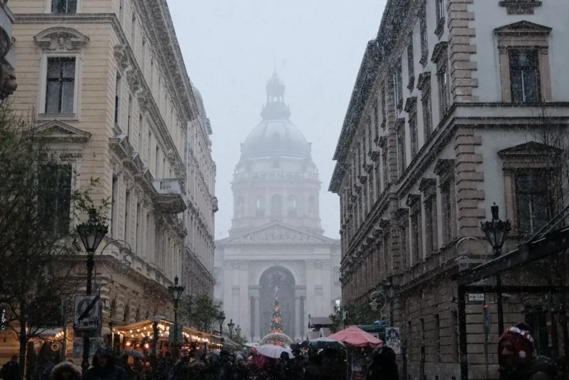 Śnieg pada na ulicach Budapesztu, tworząc zimowy klimat. W tle widać Bazylikę św. Stefana.