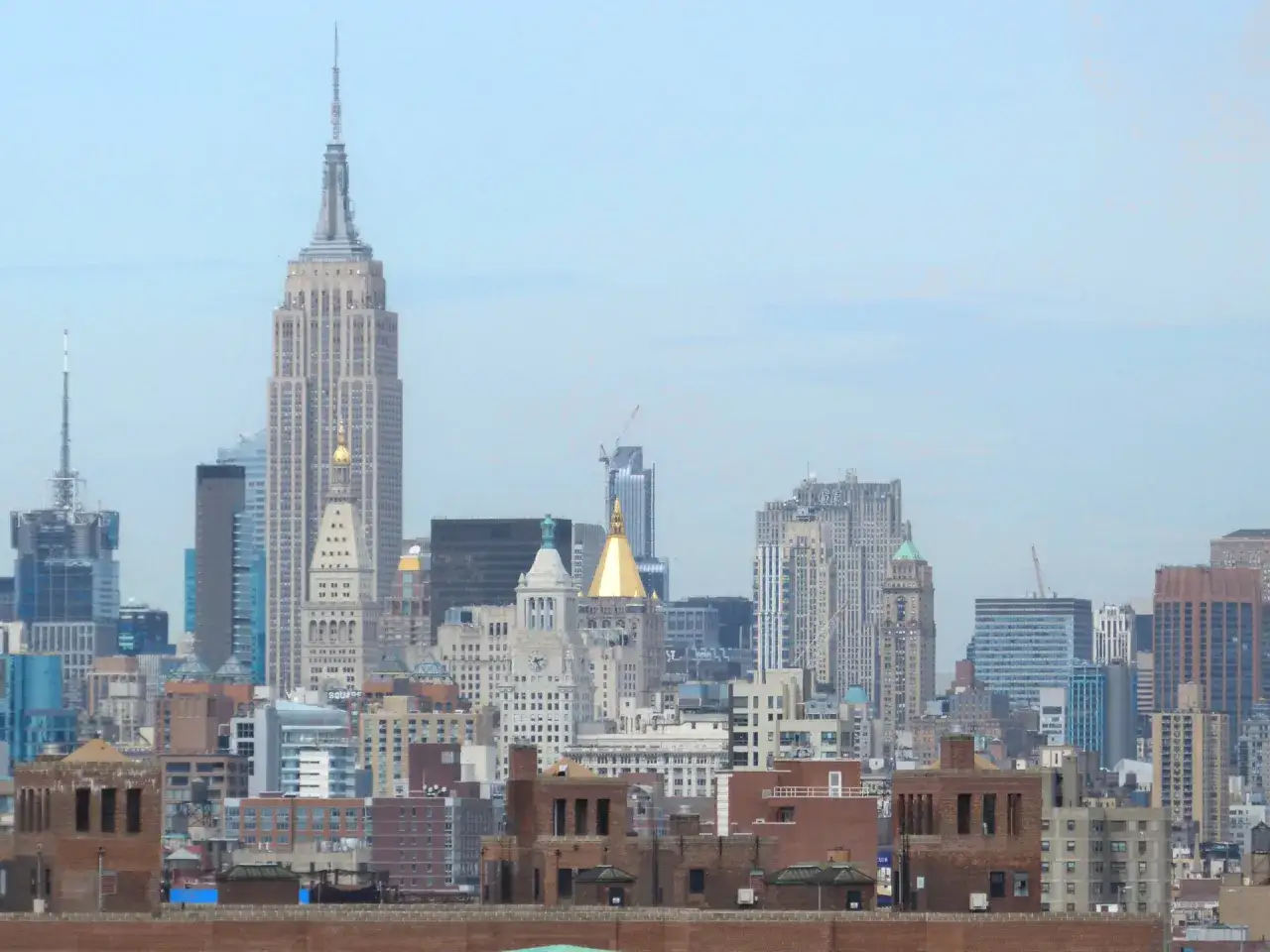 Widok na Manhattan z Empire State Building. Jego imponująca wysokość dominuje nad panoramą miasta, otoczony innymi wieżowcami.