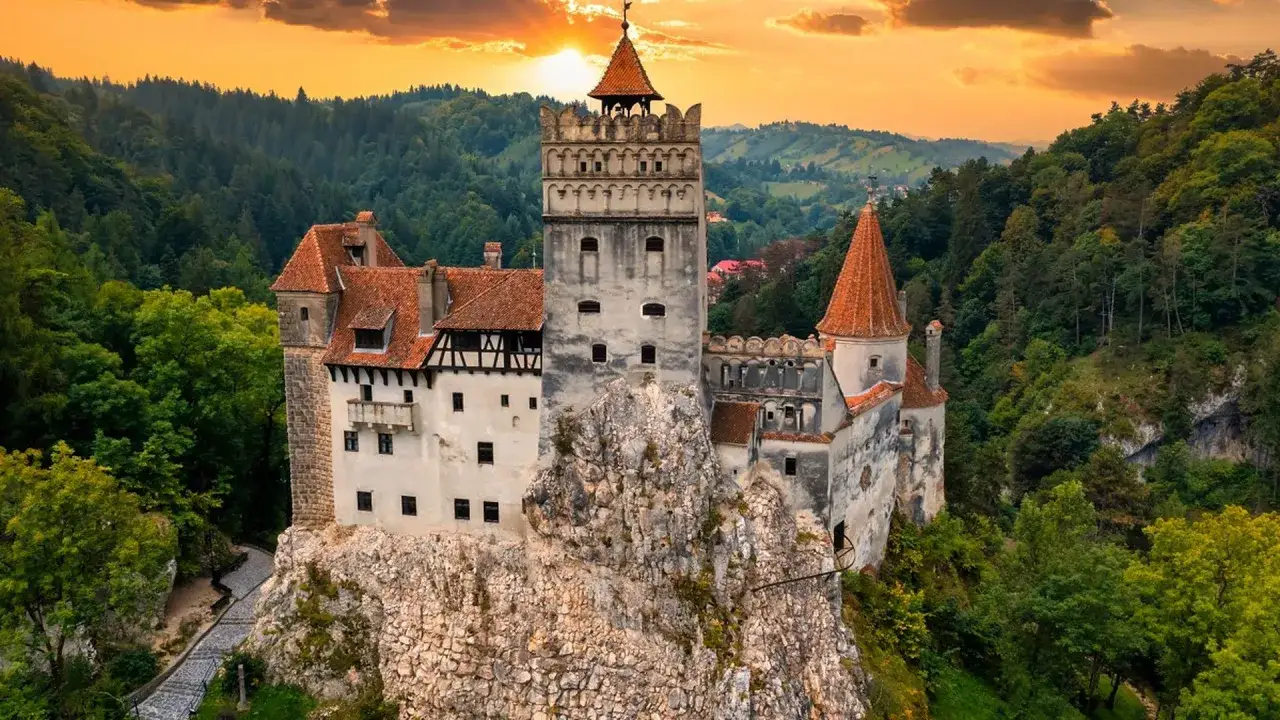Majestatyczny zamek w Transylwanii, osadzony na skale, otoczony zielonymi lasami, w blasku zachodzącego słońca.