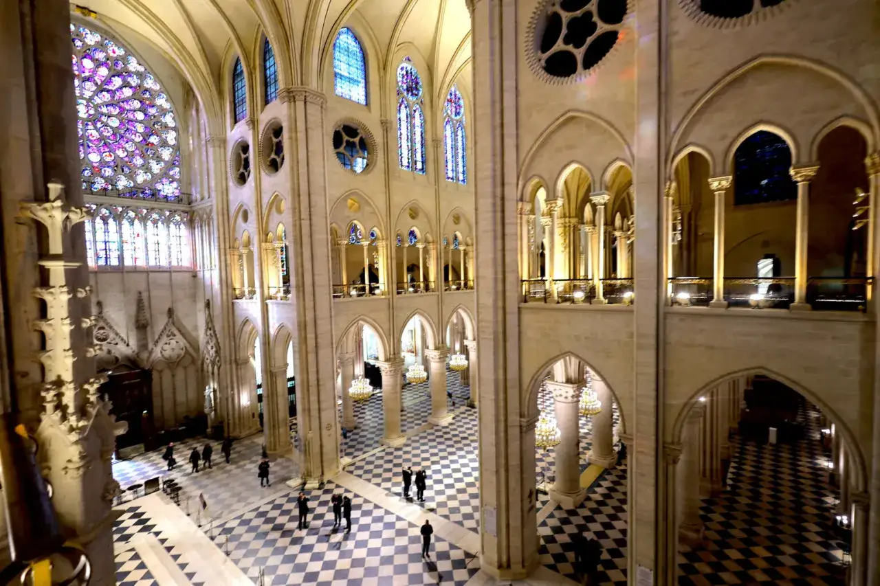 Wnętrze katedry Notre Dame dzisiaj, z widokiem na rozetę i witraże. Kamienne łuki i kolumny tworzą majestatyczną przestrzeń.