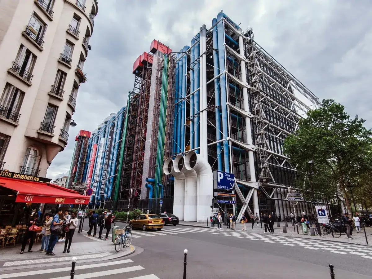 Centrum Pompidou w Paryżu, z charakterystycznymi kolorowymi rurami i stalową konstrukcją, na tle pochmurnego nieba.
